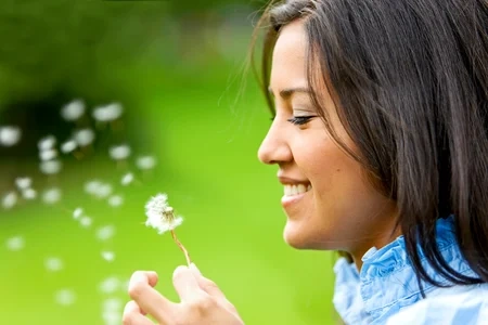 Belle femme soufflant une fleur et souriant